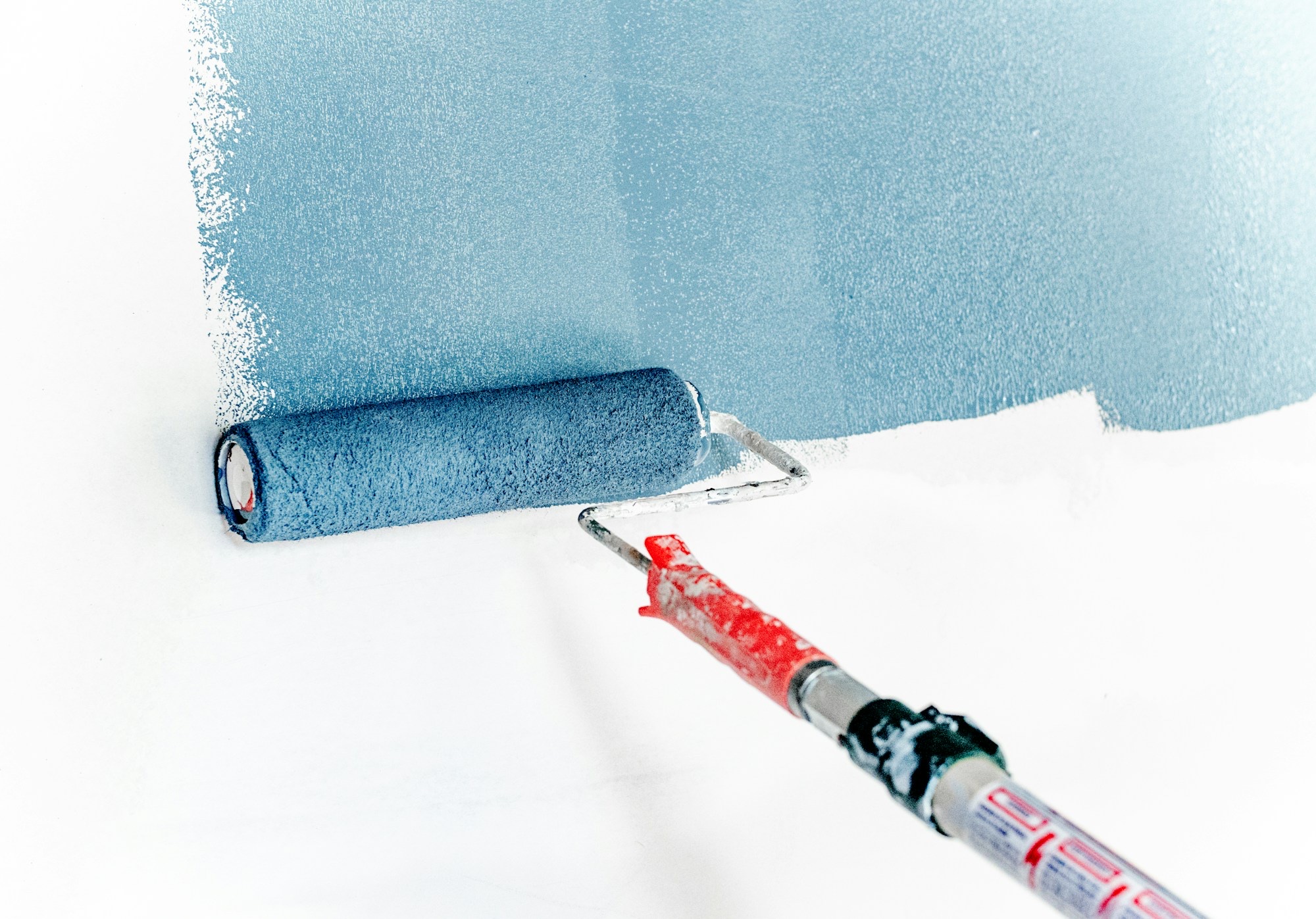 Paint roller applying blue paint to interior wall